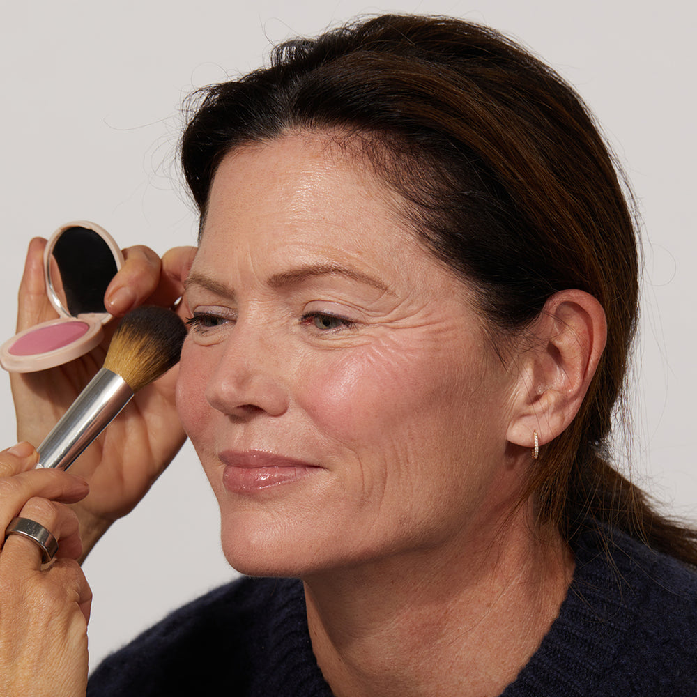 A woman having Jones Road Beauty's The Best Blush being applied to her face 