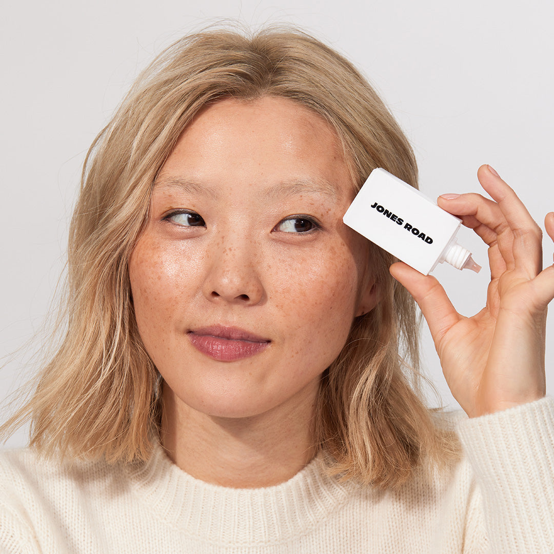 A woman showing The Gel Bronzer from Jones Road Beauty