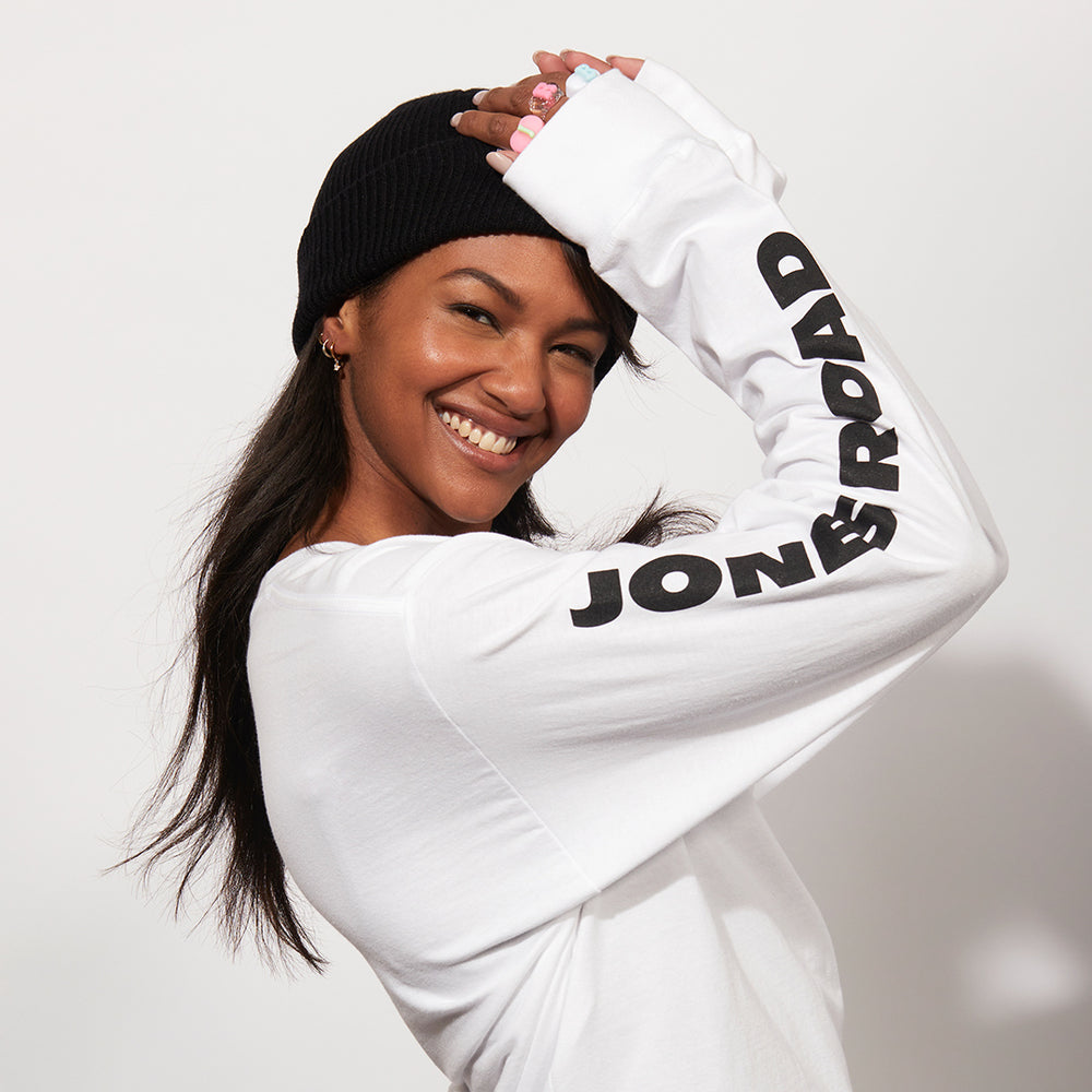 A woman wearing Jones Road Beauty apparel, including the HNTLLS shirt and The Beanie