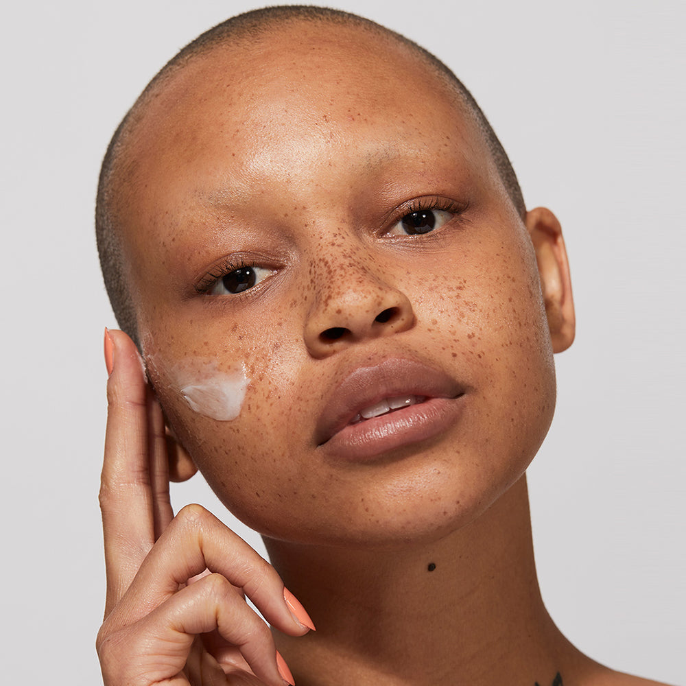 A model applying Jones Road Beauty's Light Moisture Cream to their cheeks